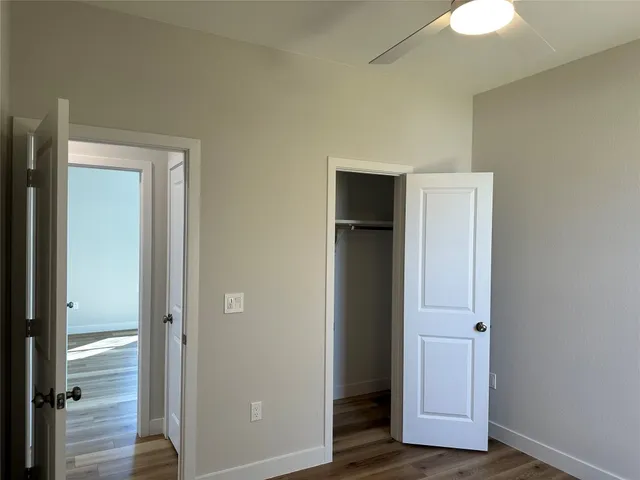 an empty room with wooden door closet and windows