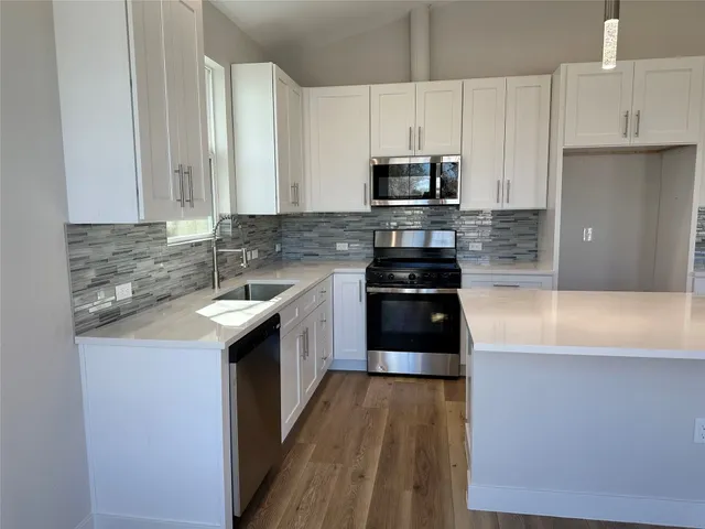 a kitchen with stainless steel appliances a sink a stove a microwave a sink a refrigerator and cabinets