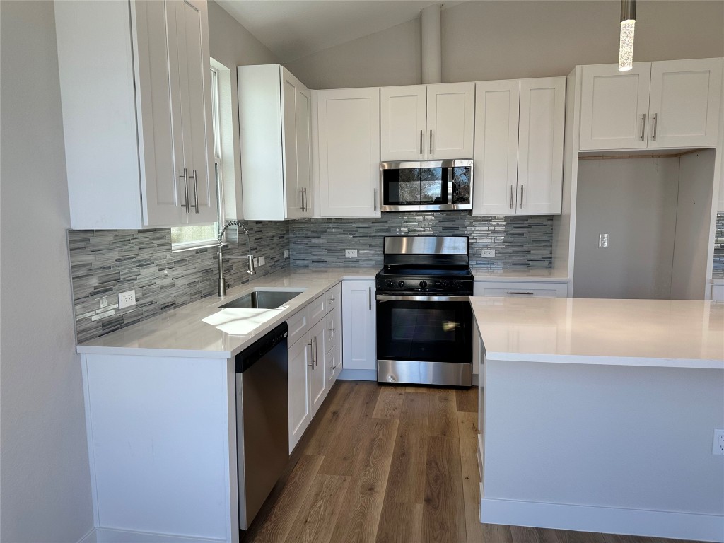 1115 Neches Street Lockhart, TX 78644 - Photo 3 of 22 a kitchen with stainless steel appliances a sink a stove a microwave a sink a refrigerator and cabinets