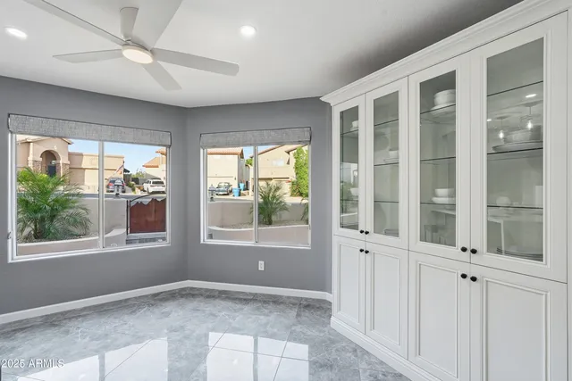 an empty room with wooden floor chandelier fan and windows