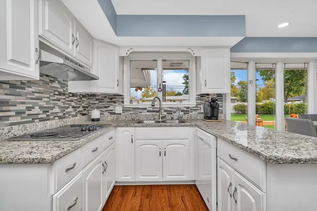 a kitchen with granite countertop white cabinets and white appliances