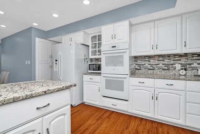 a kitchen with granite countertop white cabinets and white appliances