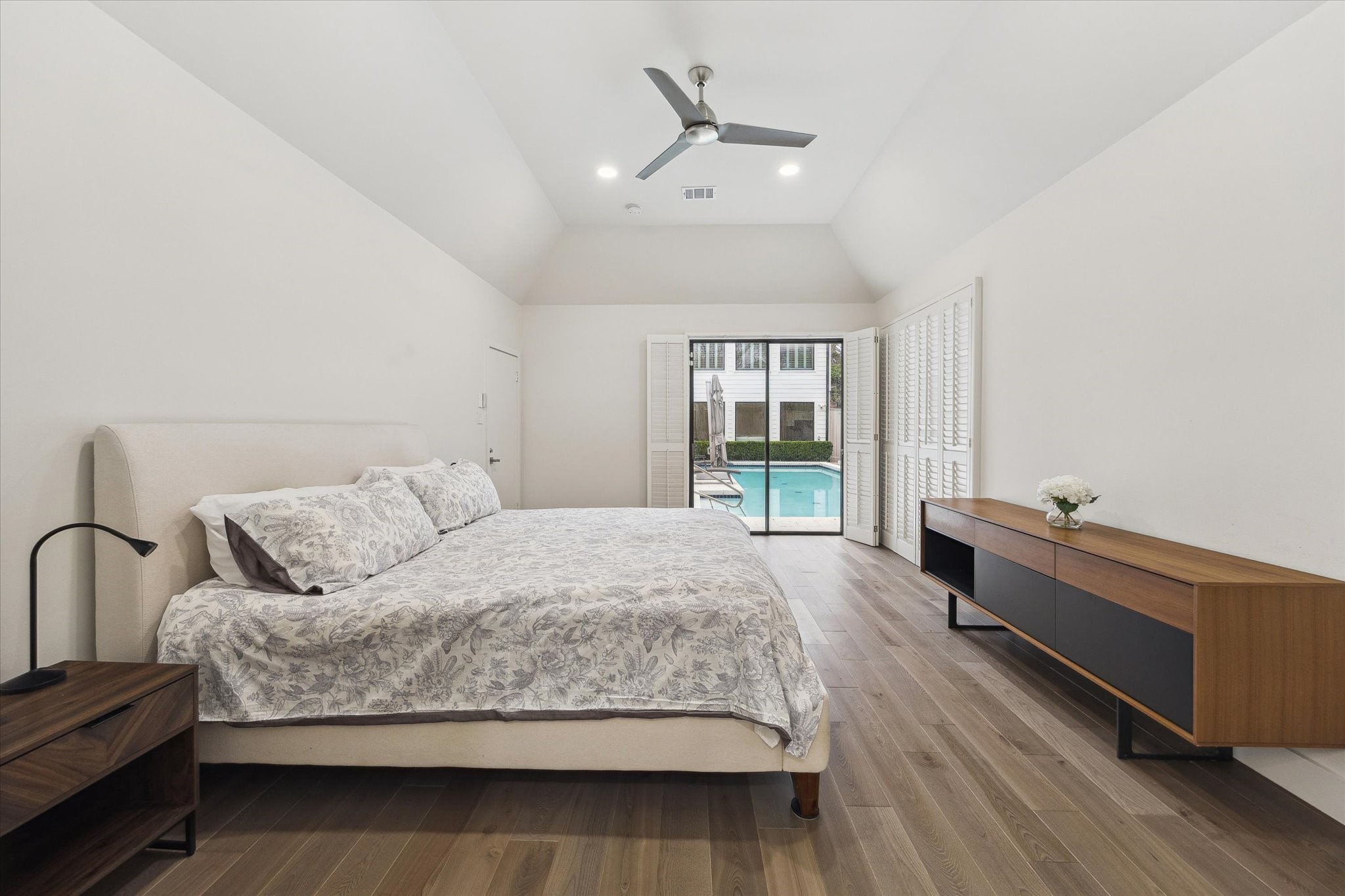 6348 Vanderbilt Street West University Place, TX 77005 - Photo 10 of 30 The primary bedroom is a true retreat. Vaulted ceilings, warm hardwood floors, and a serene neutral palette create a calm you can feel the moment you walk in. Plantation shutters frame a private sliding glass door that opens directly to the pool. Imagine waking up every day to these views.