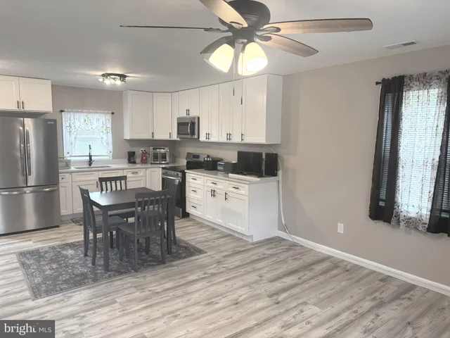 a kitchen with stainless steel appliances a dining table chairs refrigerator and cabinets