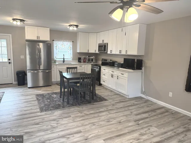 a kitchen with stainless steel appliances a dining table chairs stove refrigerator and cabinets