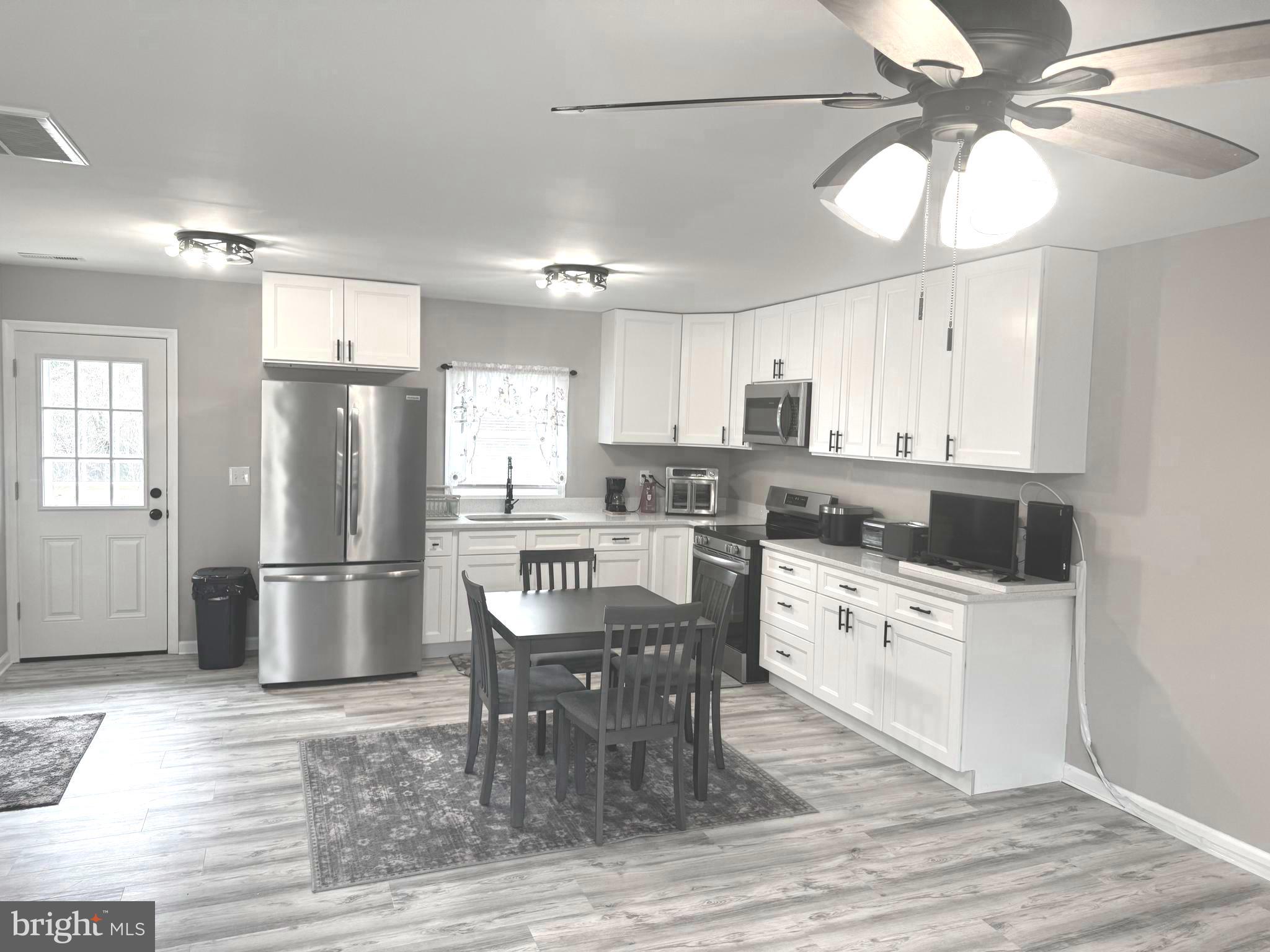 32201 Johnson Road Salisbury, MD 21804 - Photo 7 of 50 a kitchen with granite countertop a refrigerator a stove a sink and white cabinets with wooden floor