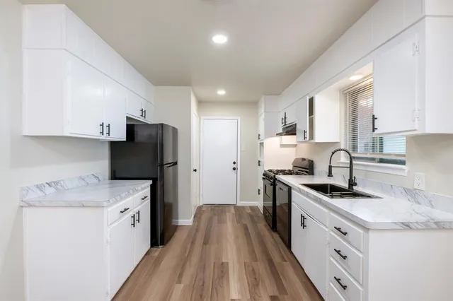a kitchen with stainless steel appliances granite countertop a sink stove refrigerator and cabinets