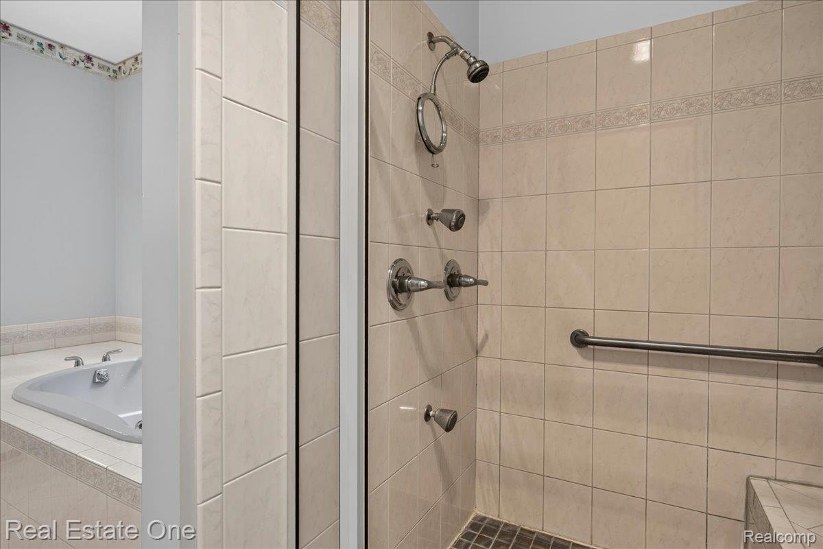 425 Courtney Road Leonard, MI 48367 - Photo 46 of 89 Enclosed shower with full-height beige tile surround, mosaic tile floor, and chrome fixtures