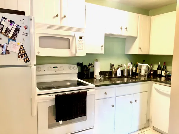 a kitchen with granite countertop white cabinets and white appliances