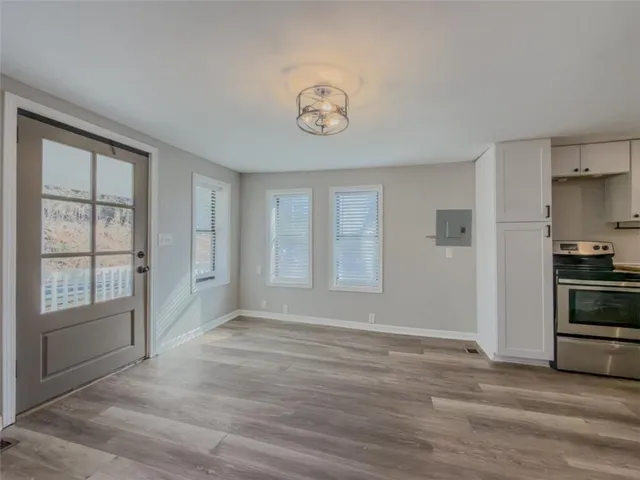 a view of an empty room with a window and wooden floor