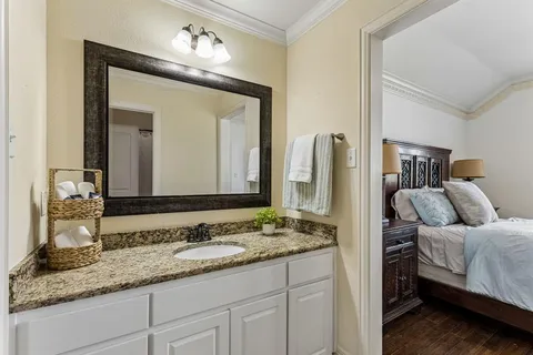 a en suite bathroom with a granite countertop sink and a mirror