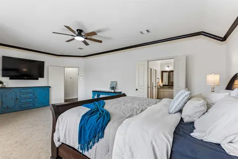 a bedroom with a large bed a flat tv screen and a ceiling fan
