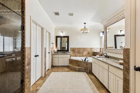 a large white bathroom with a granite countertop double vanity sink a mirror and a shower
