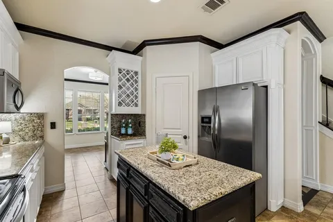 a kitchen with granite countertop a table chairs and refrigerator