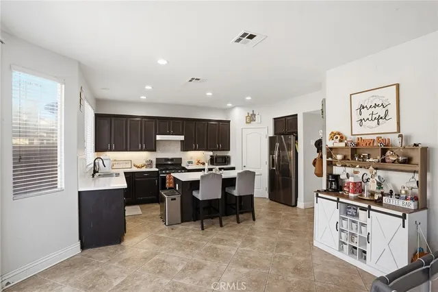 a kitchen with stainless steel appliances granite countertop a sink dishwasher a refrigerator and a stove with wooden floor