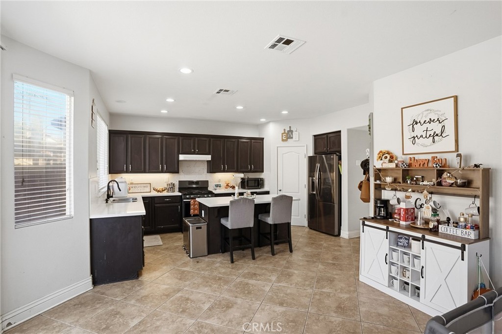 3902 Bluff Street Perris, CA 92571 - Photo 14 of 44 a room with stainless steel appliances kitchen island granite countertop a table chairs in it and a window