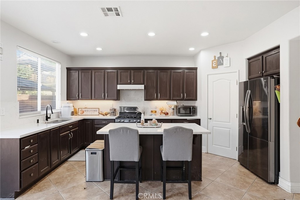 3902 Bluff Street Perris, CA 92571 - Photo 16 of 44 a kitchen with a sink a refrigerator and wooden cabinets