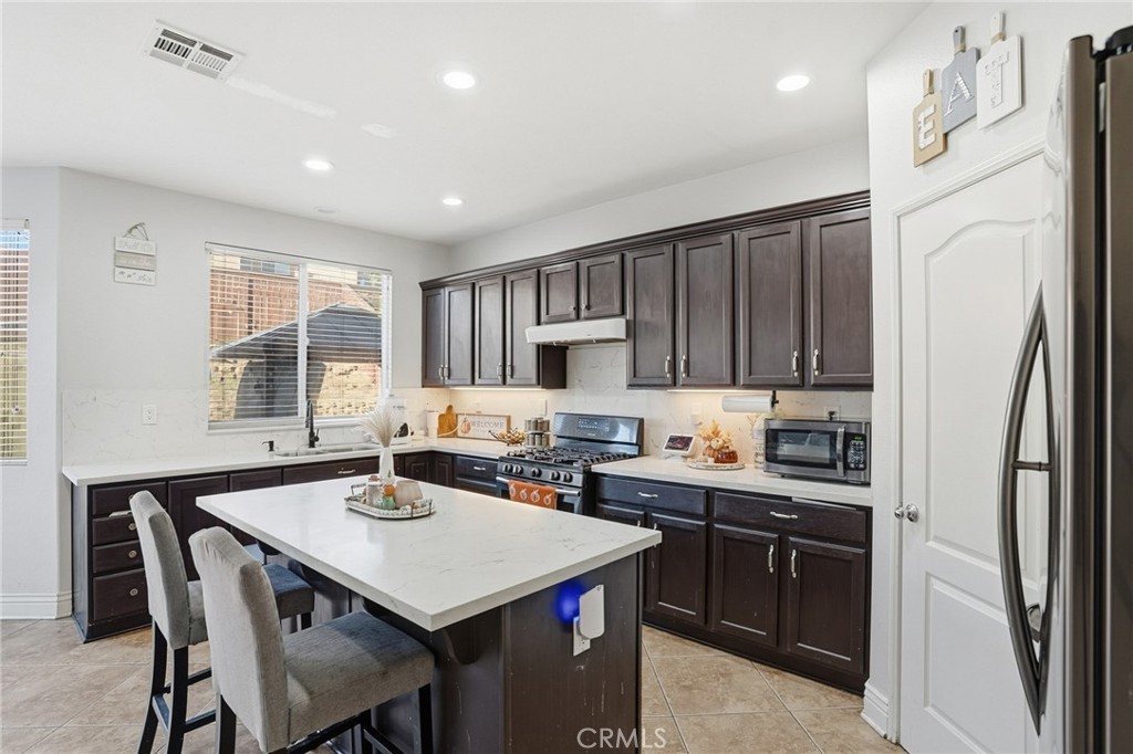3902 Bluff Street Perris, CA 92571 - Photo 17 of 44 a kitchen with a stove a refrigerator and a dining table
