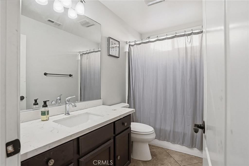 3902 Bluff Street Perris, CA 92571 - Photo 32 of 44 a bathroom with a sink a toilet a mirror and shower curtain