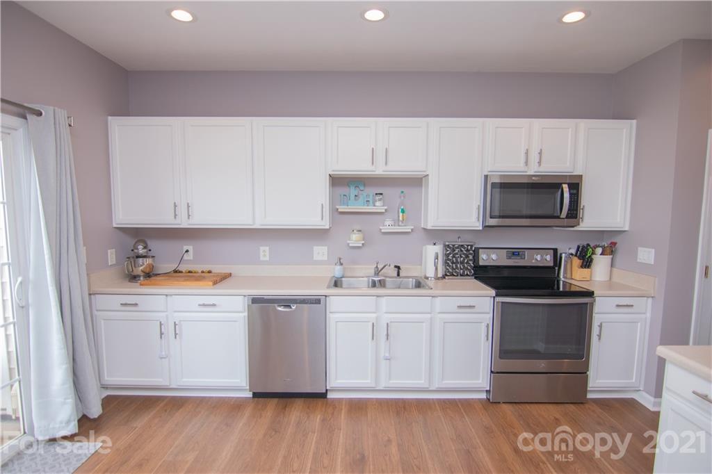 a kitchen with stainless steel appliances a stove top oven a sink a counter space and cabinets