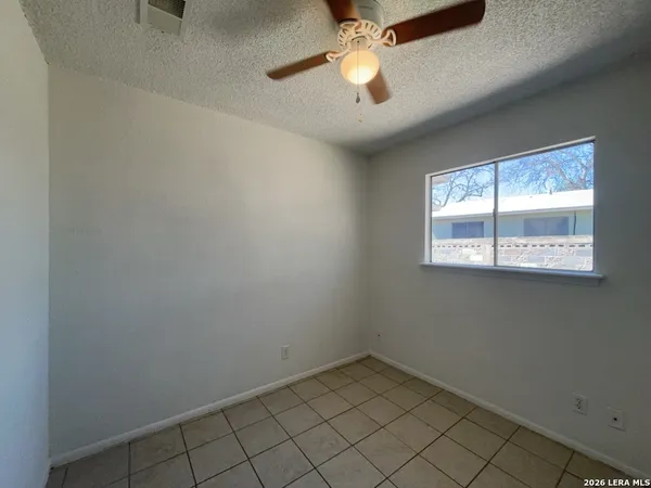 an empty room with a window and a fan
