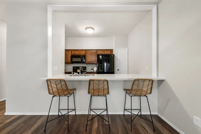 a kitchen with stainless steel appliances kitchen island granite countertop a dining table chairs and a refrigerator