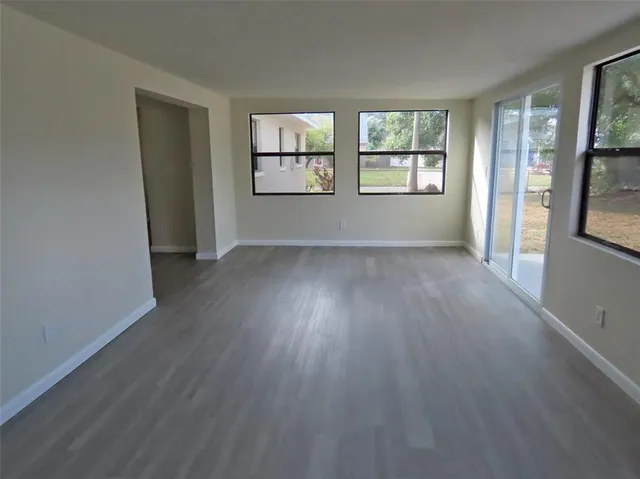 a view of an empty room with wooden floor and a window