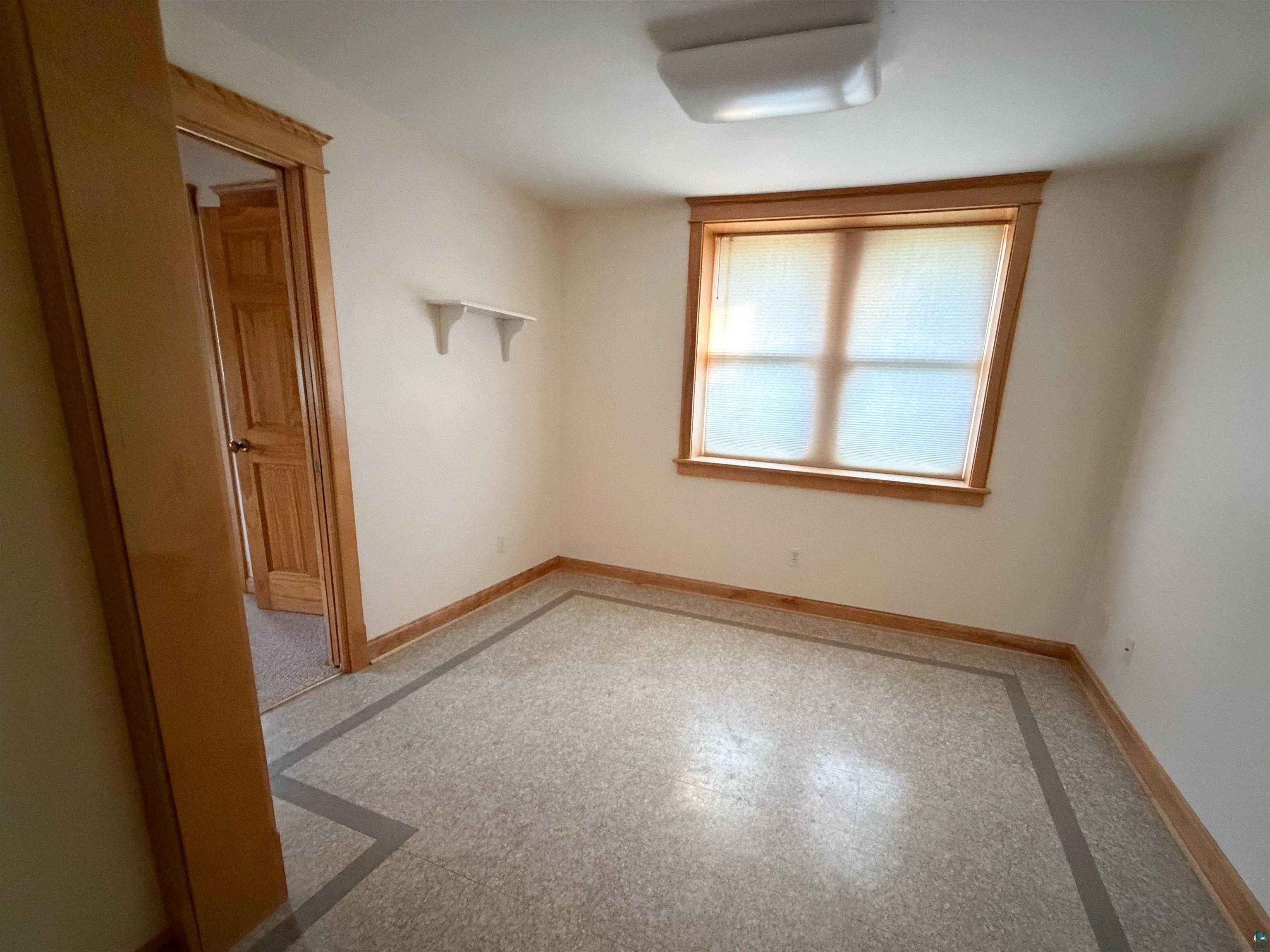 13 West 8th Street Duluth, MN 55806 - Photo 40 of 57 Neutral-toned room featuring a window with natural wood trim, a built-in shelf, and a light fixture