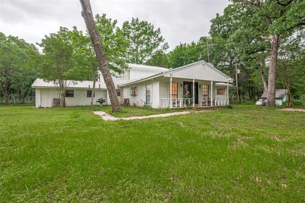 a front view of a house with a garden and trees