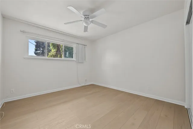 an empty room with a chandelier fan and windows