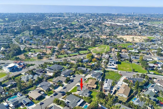 an aerial view of residential houses with outdoor space and trees