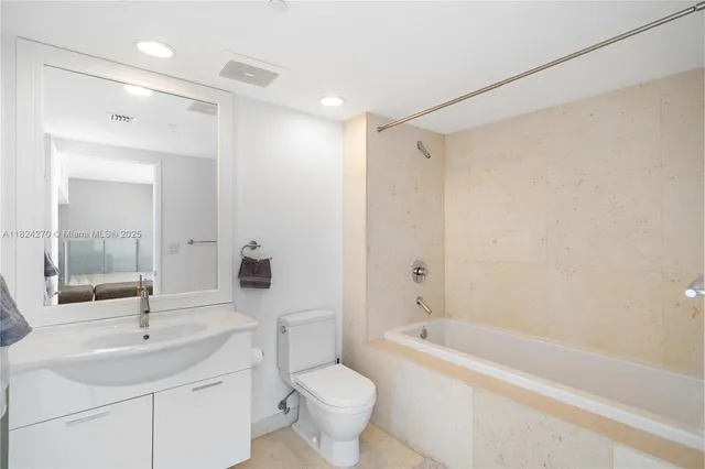 a bathroom with a bathtub shower sink vanity mirror and toilet
