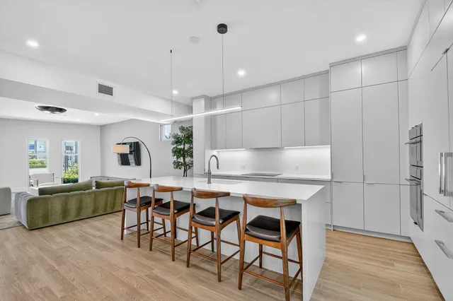 a kitchen with stainless steel appliances a table chairs refrigerator and wooden cabinets