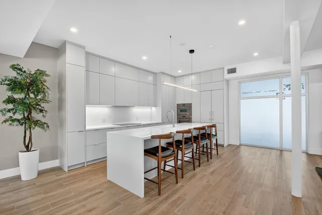 a kitchen with kitchen island a wooden floor stainless steel appliances and cabinets