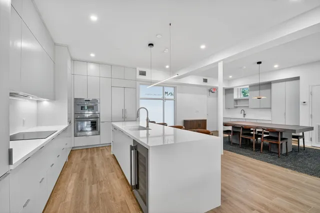 a large white kitchen with kitchen island a dining table and a large window