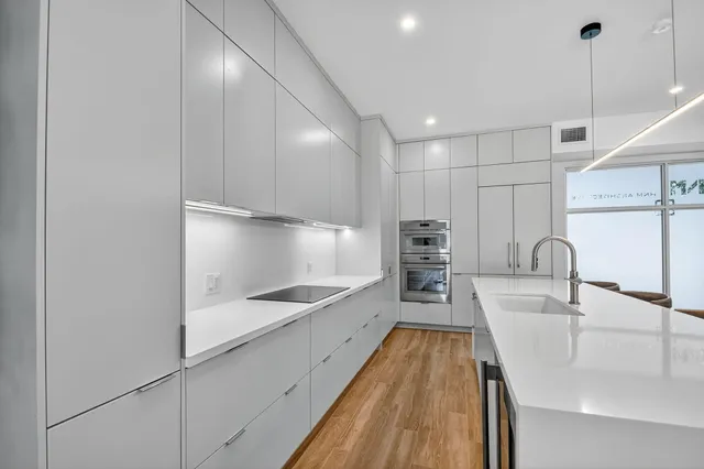 a kitchen with kitchen island a counter top space a sink stainless steel appliances and cabinets