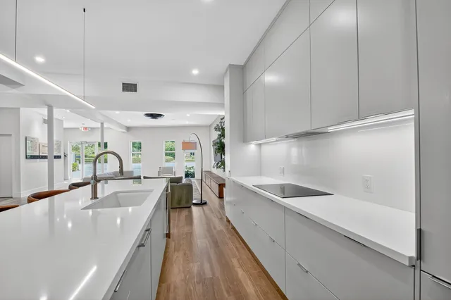 a large white kitchen with a large window and stainless steel appliances