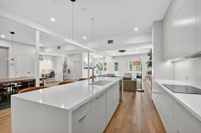 a large white kitchen with a large counter top furniture appliances and a window