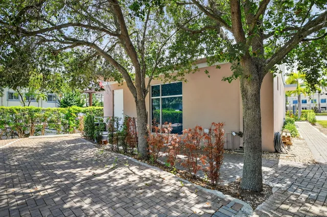 a backyard of a house with large trees and plants
