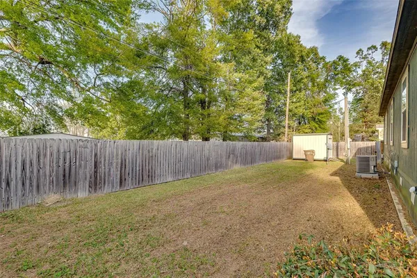 a view of a backyard with trees and wooden fence