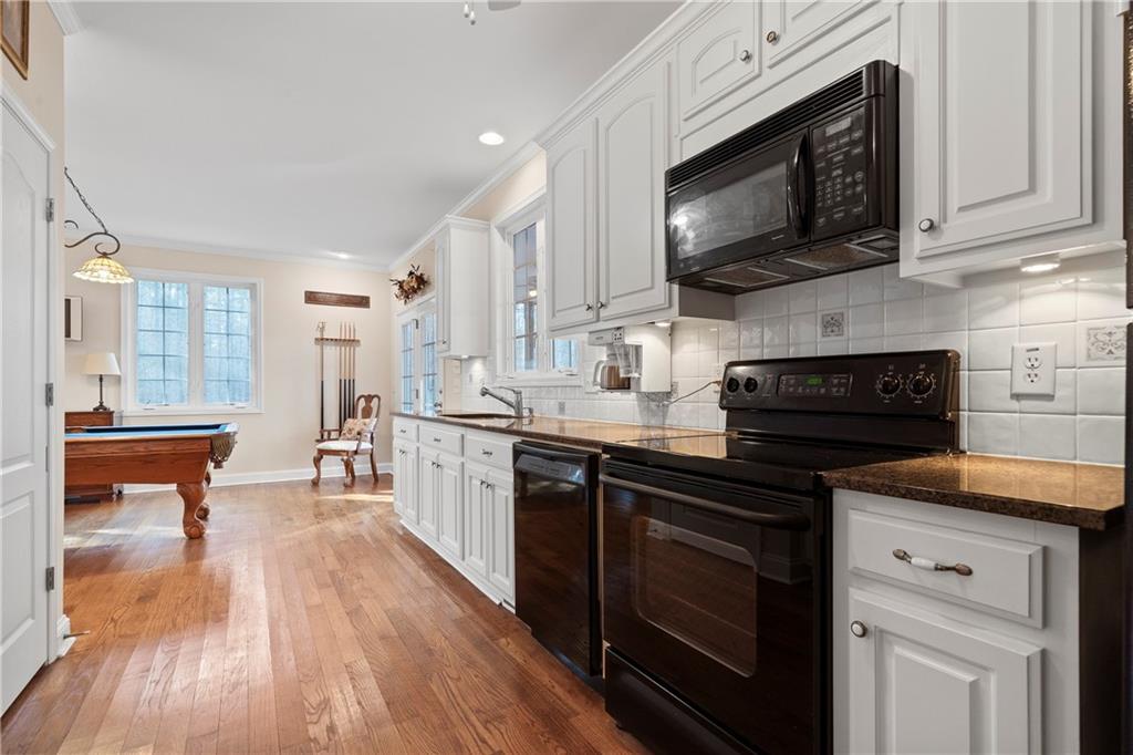 125 Lowe Road Northwest Milledgeville, GA 31061 - Photo 23 of 62 a kitchen with stainless steel appliances wooden cabinets granite counter tops a stove a sink and a wooden floors