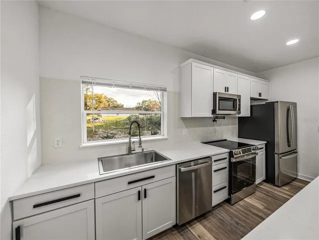 a kitchen with kitchen island granite countertop white cabinets and stainless steel appliances