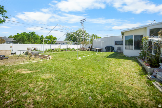 3233 Jean Street Magna, UT 84044 - Photo 31 of 33 Expansive rear yard featuring green lawn, white privacy fencing, and concrete-block planter boxes