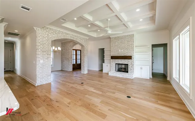 an empty room with wooden floor fireplace and windows
