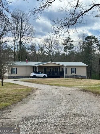 a front view of a house with a garden and trees