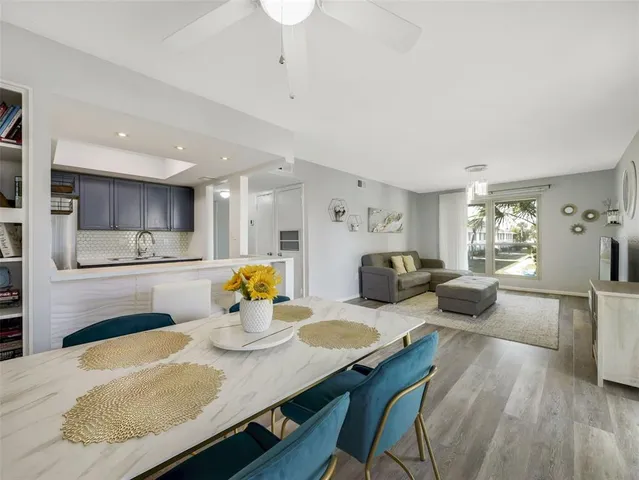 a kitchen with stainless steel appliances granite countertop a stove a sink dishwasher a dining table and chairs with wooden floor