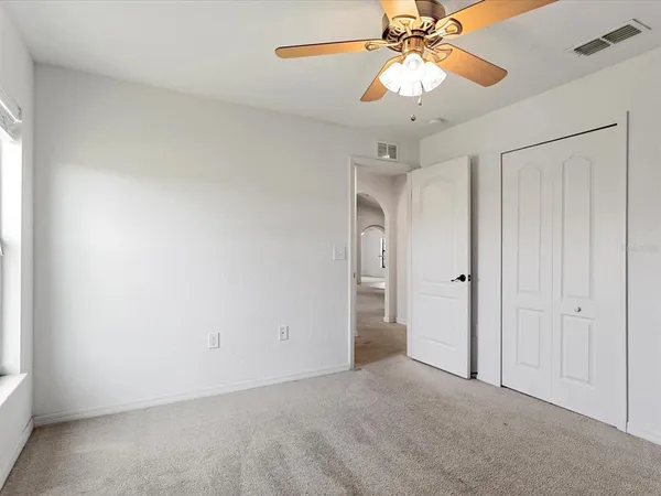 an empty room with a chandelier fan and closet