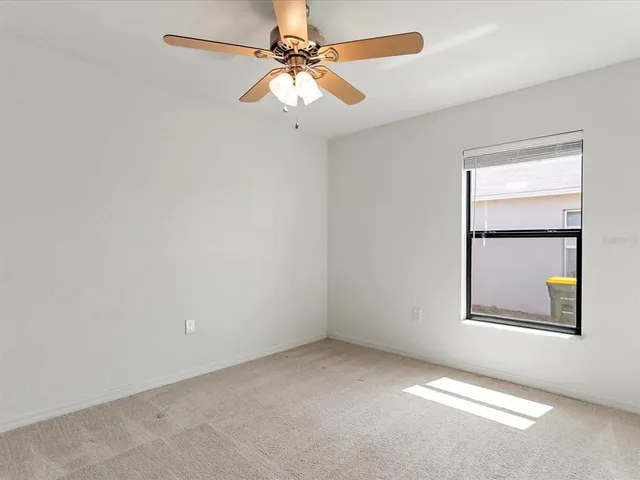 an empty room with a window and a fan