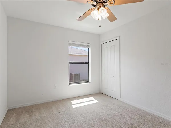 an empty room with windows and chandelier fan