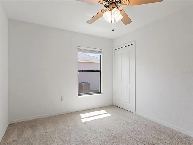 an empty room with windows and chandelier fan